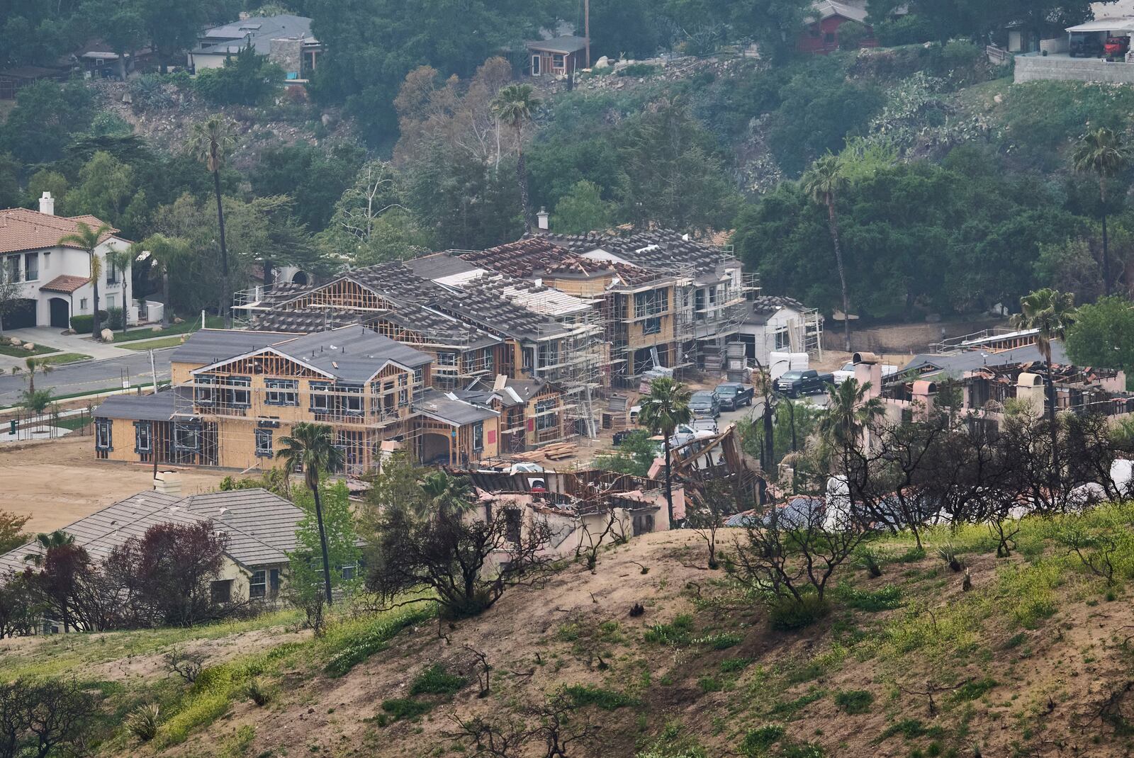 New homes are built next to burned homes at La Viña gated community adjacent to the Chaney Trail Corridor, in an area affected by the Eaton Fire, in Altadena, Calif., on Wednesday, April 23, 2025. (AP Photo/Damian Dovarganes)