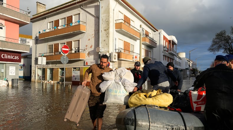 Residents of a hotel are evacuated by police officers and marines by inflatable boat along a flooded street after the Sado River overflowed following heavy rains in Alcácer do Sal, southern Portugal, Friday, Feb. 6, 2026. (AP Photo/Ana Brigida)