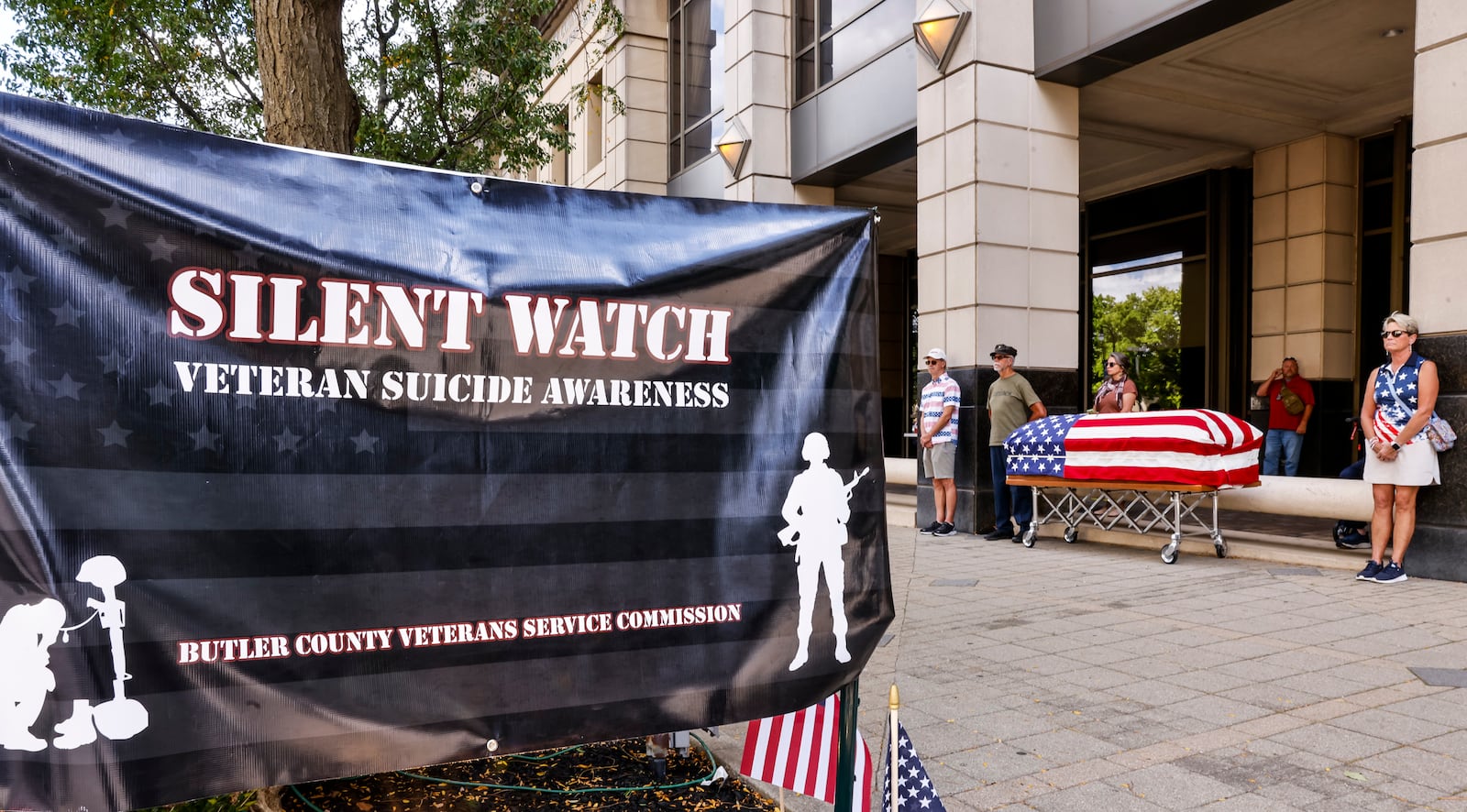 Volunteers stand near a flag draped casket to participate in a Silent Watch for veteran suicide awareness Wednesday, Sept. 18, 2024 outside the Butler County Veterans Service Commission office on High Street in Hamilton. NICK GRAHAM / STAFF