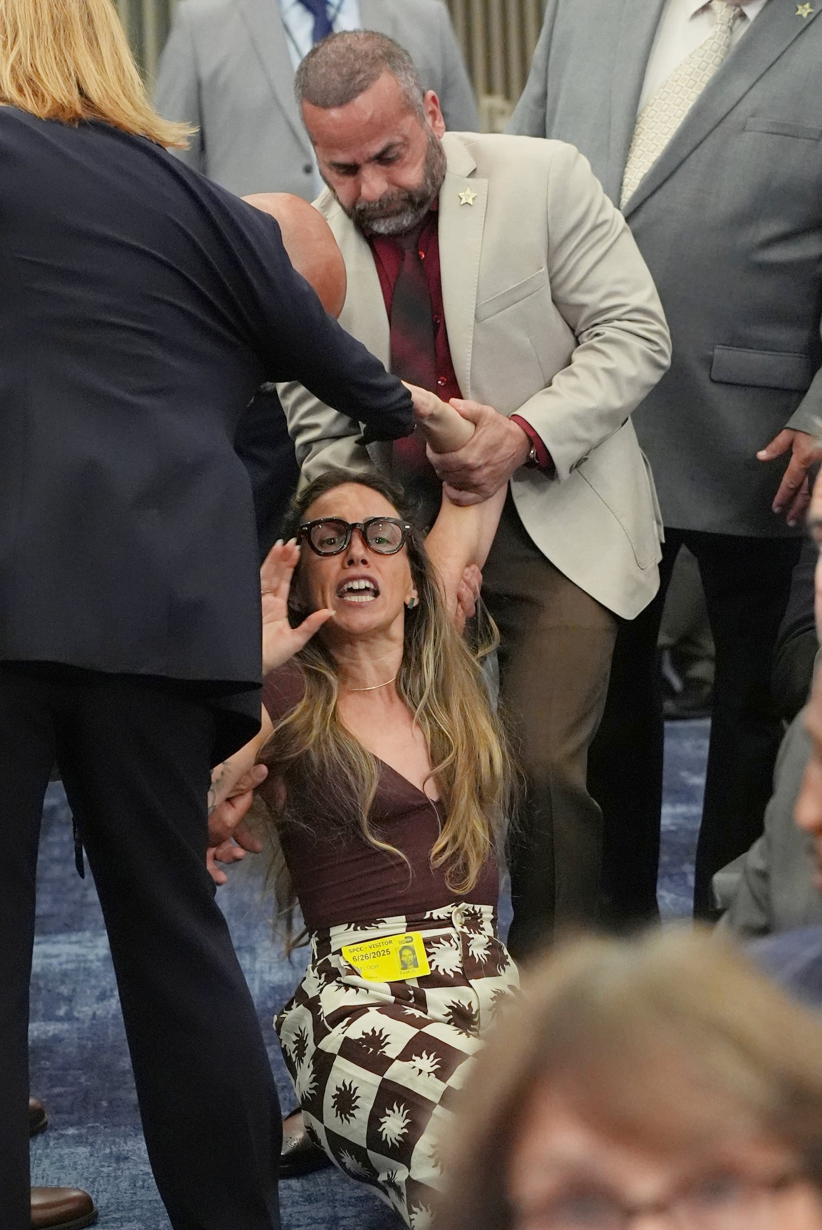 Camila Ramos is forcibly removed from a Miami Dade County Commissions meeting after they deferred a hearing relating to an agreement with ICE that advocacy groups say would make it harder for families to track undocumented immigrants once they are in custody, Thursday, June 26, 2025, in Miami. (AP Photo/Marta Lavandier)
