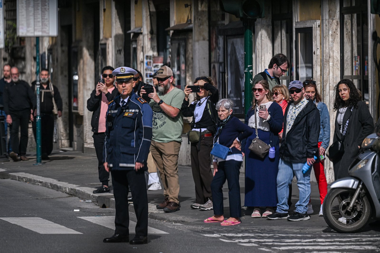 People look on as the motorcade of U.S. Vice President JD Vance passes by en route to Vatican where Vance will meet with Cardinal Pietro Parolin and Archbishop Paul Gallagher, in Rome, Italy, Saturday, April 19, 2025. (Kenny Holston/Pool Photo via AP)