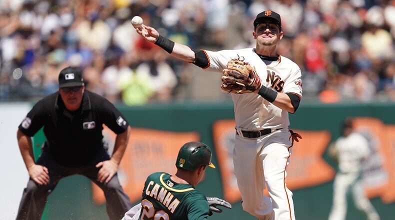 SAN FRANCISCO, CA - AUGUST 14: Scooter Gennett #14 of the San Francisco Giants completes the double-play throwing over the top of Mark Canha #20 of the Oakland Athletics in the top of the fifth inning at Oracle Park on August 14, 2019 in San Francisco, California. (Photo by Thearon W. Henderson/Getty Images)