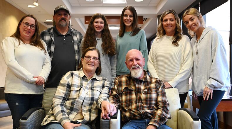 Clay Calihan, seat at right, was diagnosed with melanoma cancer in his left lung in the summer of 2023. The tumor is unable to be removed, and he and his doctors elected to treat it with immunotherapy instead of total removal of his lung as the cancer is wrapped around his pulmonary artery. Calihan is pictured with his partner of 32 years, Stephanie Lentz, and some of Calihan's children and grandchildren at Kettering Health Hamilton where he receives treatments, which likely would continue for the rest of his life. MICHAEL D. PITMAN/STAFF