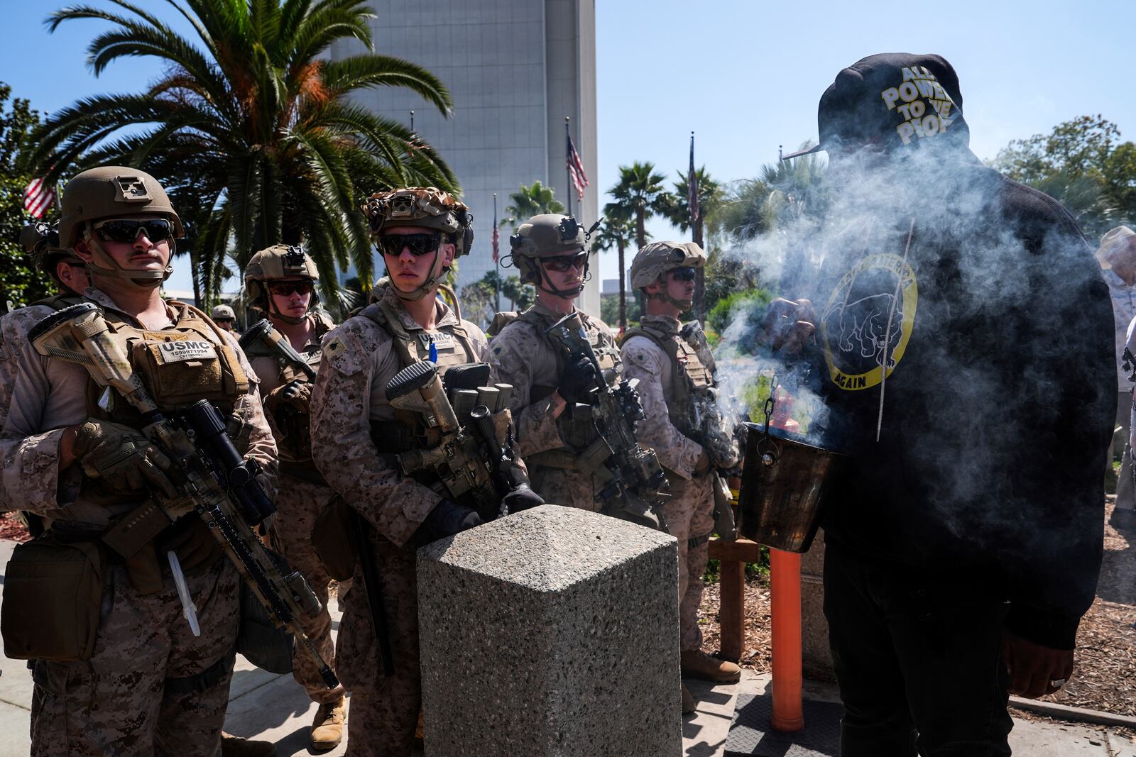Erik, who only gave his first name, burns incense as he confronts U.S. Marines guarding the Wilshire Federal Building in Los Angeles Sunday, June 22, 2025, while anti-war demonstrators protest U.S. airstrikes on Iran's nuclear facilities. (AP Photo/Jae C. Hong)