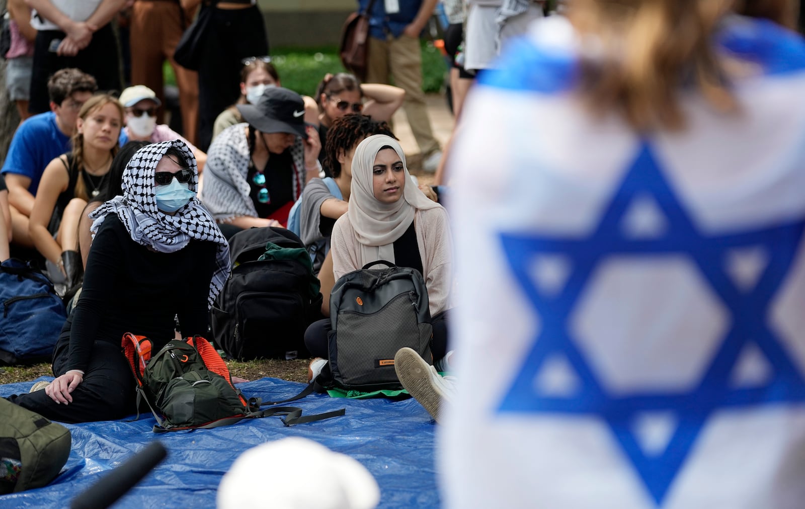 FILE - A student wrapped in an Israeli flag listens to Pro-Palestinian protesters gathered on campus at the University of Texas at Austin, on April 30, 2024, in Austin, Texas. (AP Photo/Eric Gay, File)