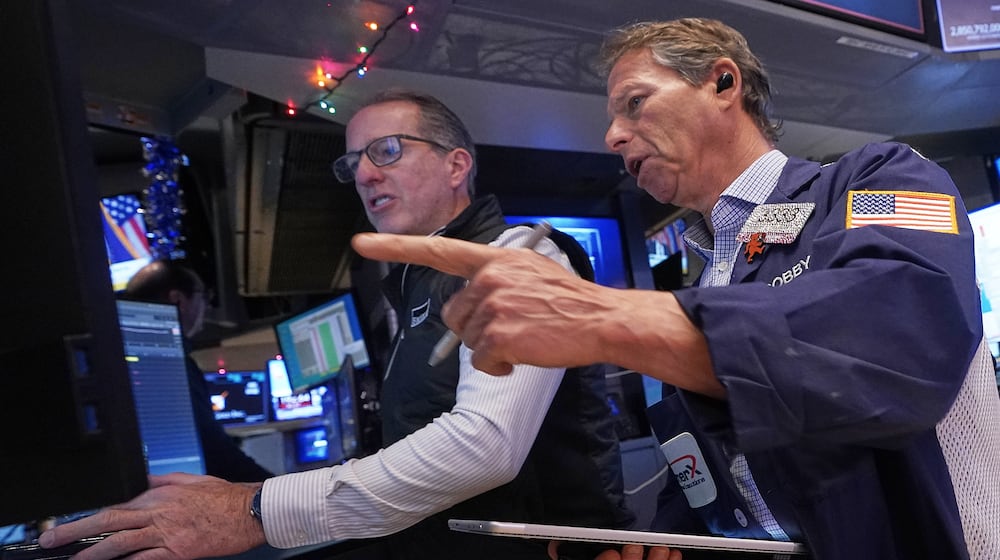 Specialist Glenn Carell, left, and trader Robert Charmak work on the floor of the New York Stock Exchange, Thursday, Dec. 11, 2025. (AP Photo/Richard Drew)