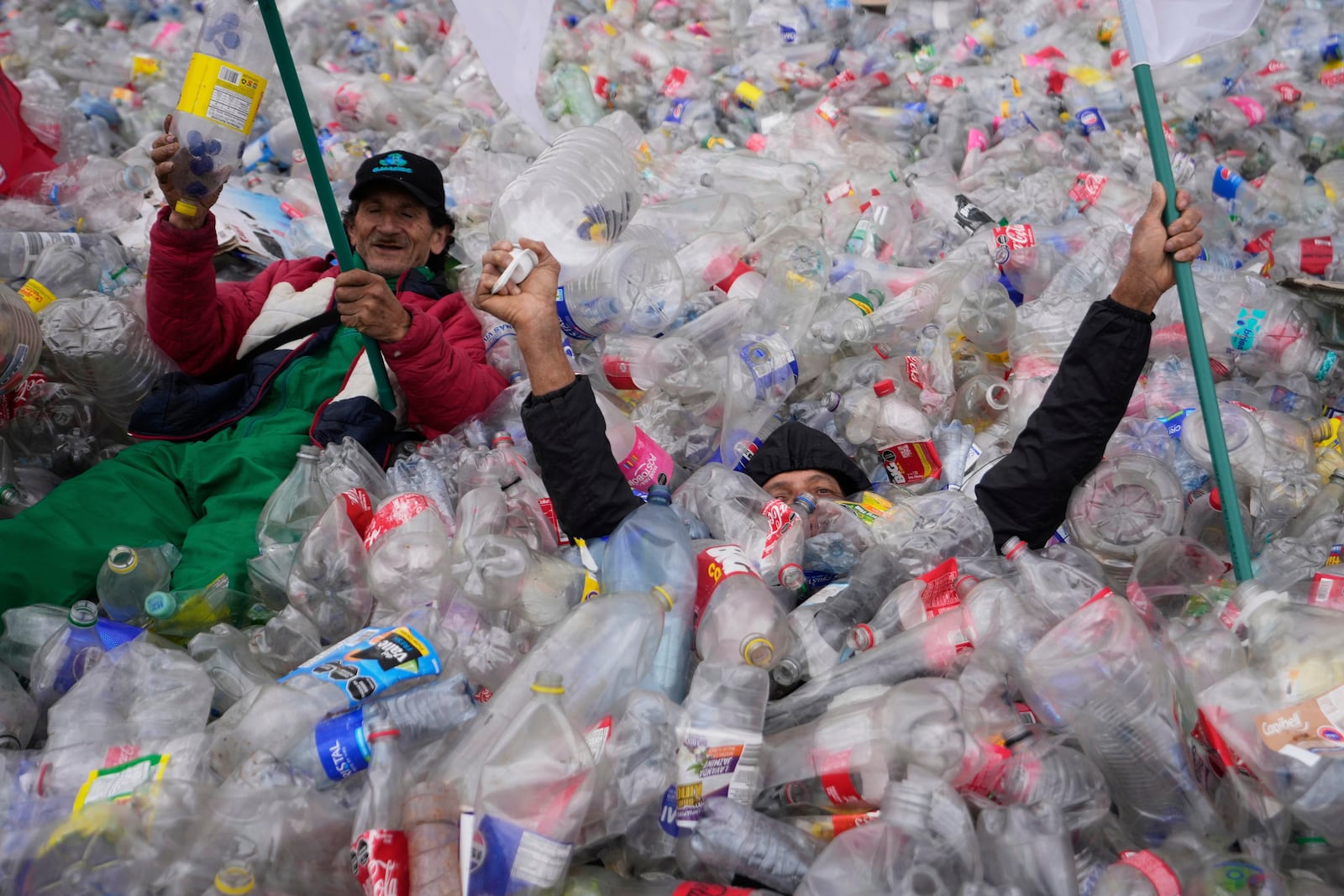 Recyclers lie on plastic bottles blanketing Plaza Bolivar in Bogota, Colombia, as part of a protest against what recyclers consider to be too low a price paid to them by companies that buy recycled materials, Tuesday, June 24, 2025. (AP Photo/Fernando Vergara)