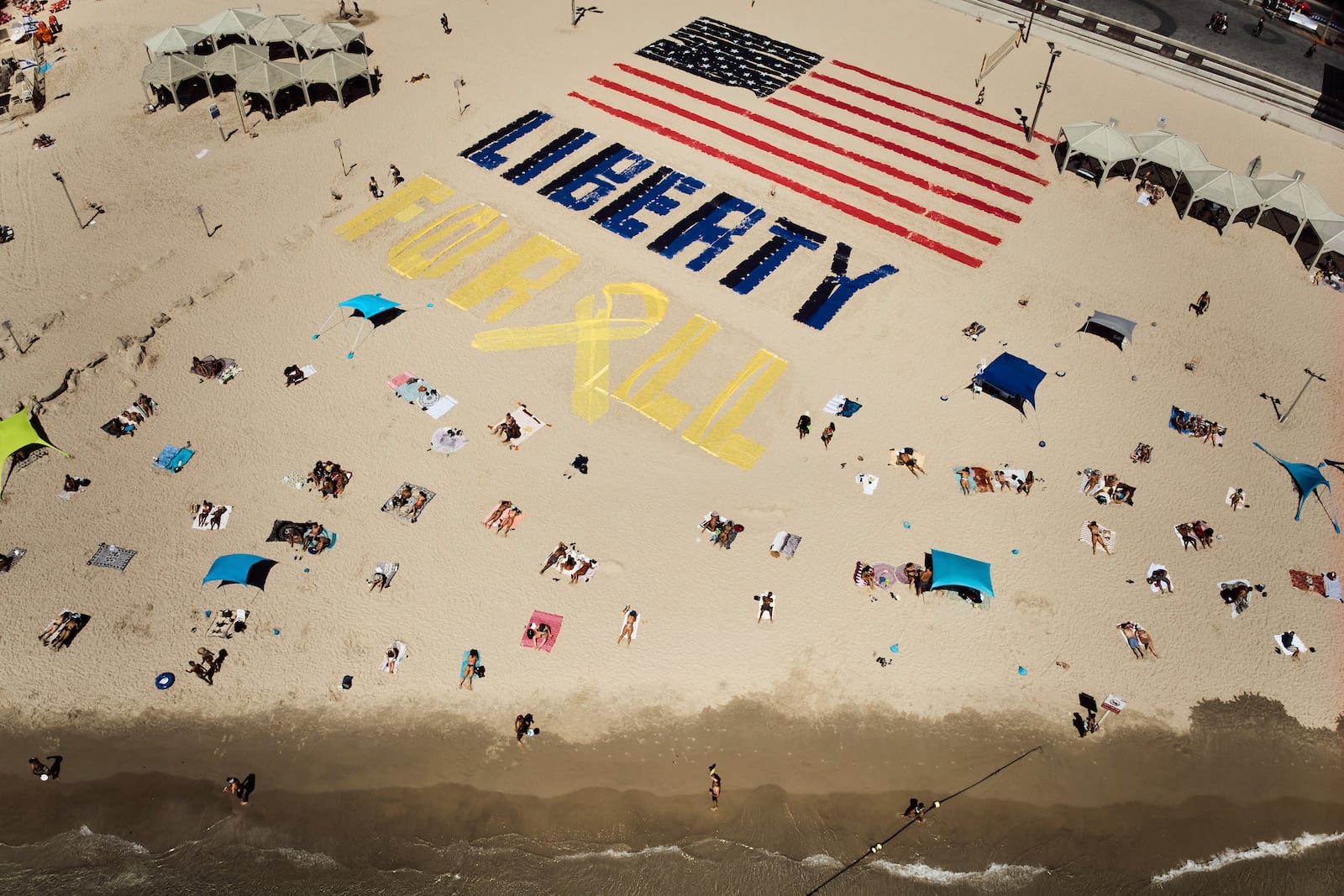 An installation with the U.S. flag and the message "liberty for all," which was created by relatives and supporters of Israelis held captive in the Gaza Strip, calls for their release and urges a ceasefire on the beach in Tel Aviv, Israel, on Friday, July 4, 2025. (AP Photo/Oded Balilty)