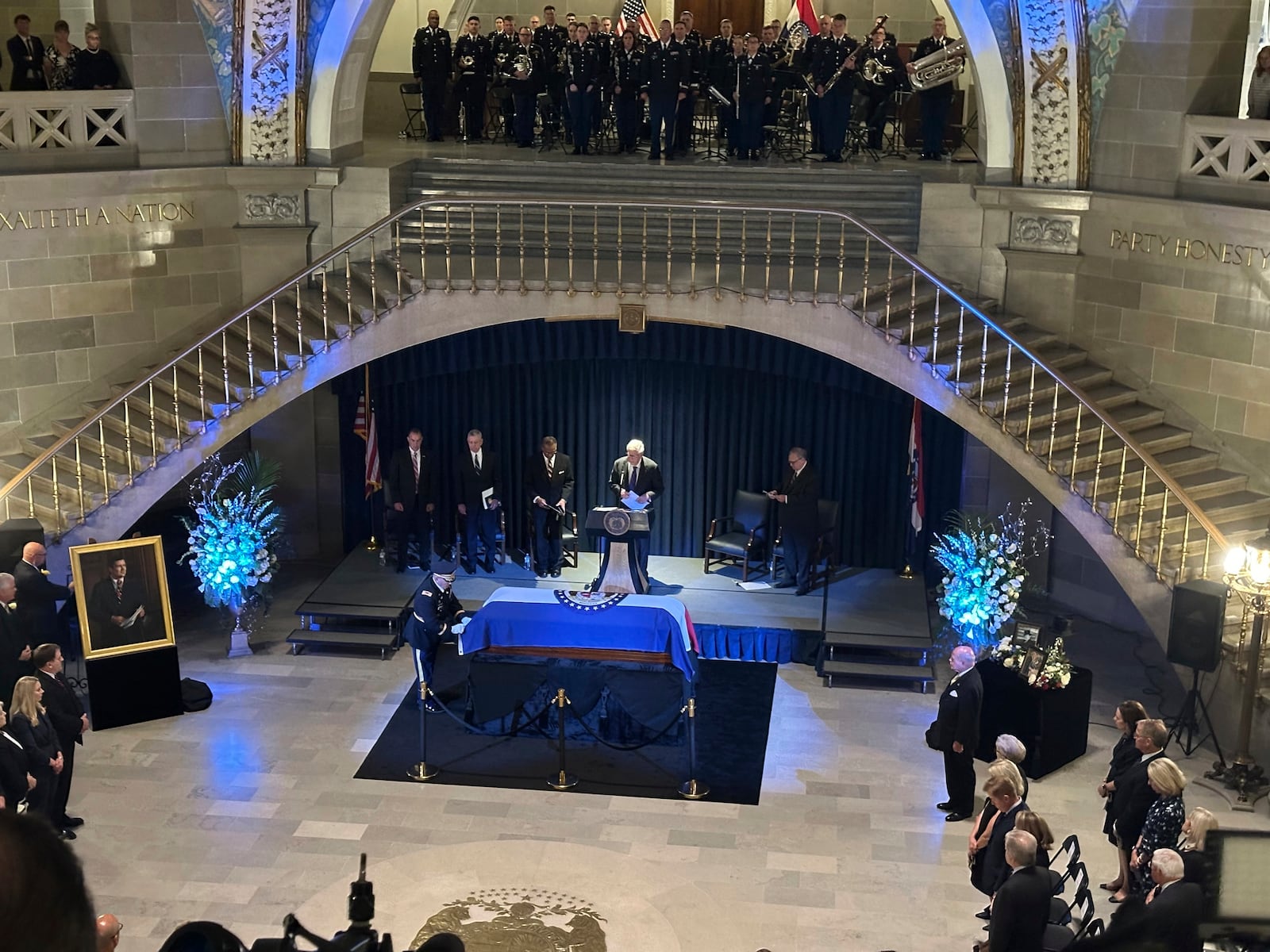 An officer stands by the casket of former Missouri Gov. and U.S. Sen. Christopher "Kit" Bond as former U.S. Sen. John Danforth prepares to speak at a memorial service for Bond on Tuesday, May 20, 2025, in the Missouri Capitol in Jefferson City, Mo. (AP Photo/David A. Lieb)