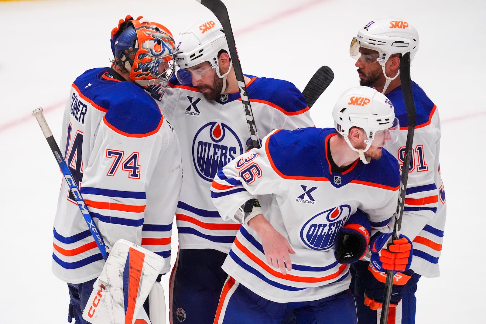 Edmonton Oilers goaltender Stuart Skinner (74) gathers with teammates, from left defenseman Evan Bouchard, defenseman John Klingberg (36) and left wing Evander Kane (91) following a 3-0 win over the Dallas Stars in Game 2 of the Western Conference finals in the NHL hockey Stanley Cup playoffs, Friday, May 23, 2025, in Dallas. (AP Photo/LM Otero)