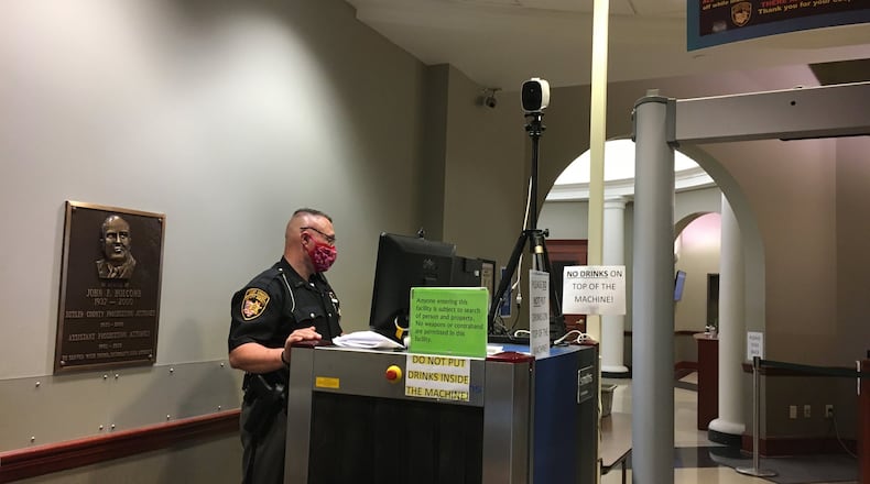 Butler County Sheriff’s Deputy Melvin Noes stands at the monitor at the security check point at the court wing of county common pleas court Tuesday. A new thermal imaging camera that takes the temperature of everyone who passes in front of it sits on top of the X-ray machine. LAUREN PACK/STAFF