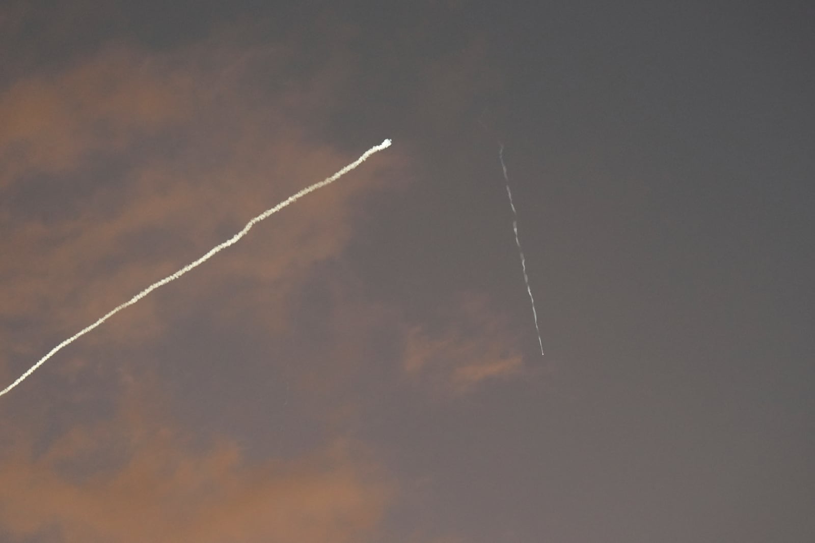 A smoke trail from the Israeli Iron Dome air defense system streaks across the sky as it intercepts missiles launched during an Iranian attack, as seen from Haifa, Israel, early Tuesday, June 24, 2025. (AP Photo/Baz Ratner)