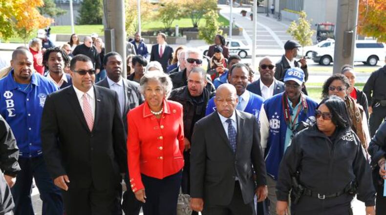 Civil right icon, U.S. Rep. John Lewis (center) leads a group to the Montgomery County Board of Elections Friday for early voting after speaking at a rally at Sinclair Community College. At left is U.S. Rep. Joyce Beatty, D-Columbus. attended a get out the vote rally at Sinclair Community College in Dayton Friday. LISA POWELL / STAFF