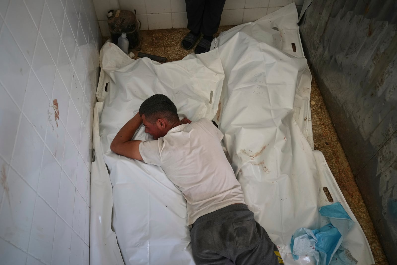 Youssef Abd Rabbo cries over the body of his mother, Manal Abd Rabbo, who was among 10 people, including two women and five children, killed in an Israeli strike while they were waiting to receive nutritional supplements at a Project Hope-run medical clinic in Deir al-Balah, Gaza Strip, Thursday, July 10, 2025. (AP Photo/Abdel Kareem Hana)