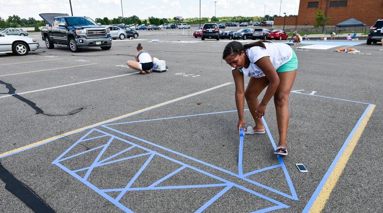 Riana Spiller, a Lakota East senior, masks off her school parking spot in preparation for paint. NICK GRAHAM/STAFF
