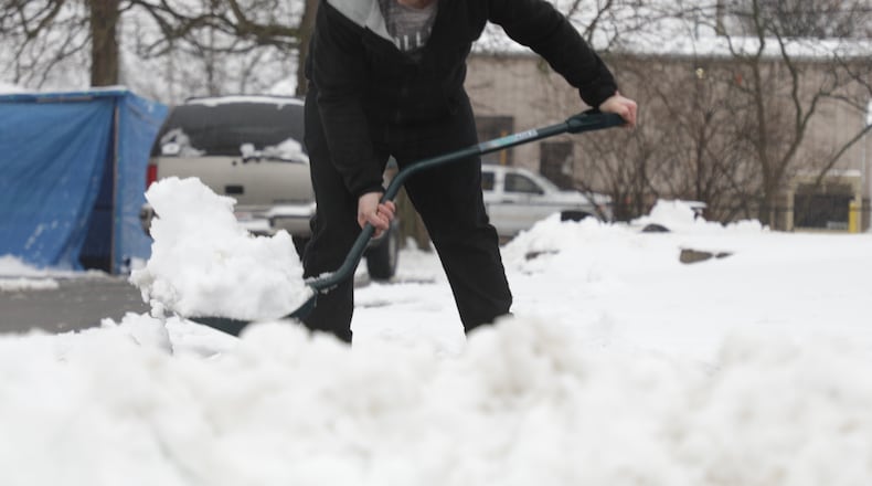 Mike Fent shovels heavy snow off the parking lot of the Bethel Apostolic Church in Springfield. BILL LACKEY/ STAFF
