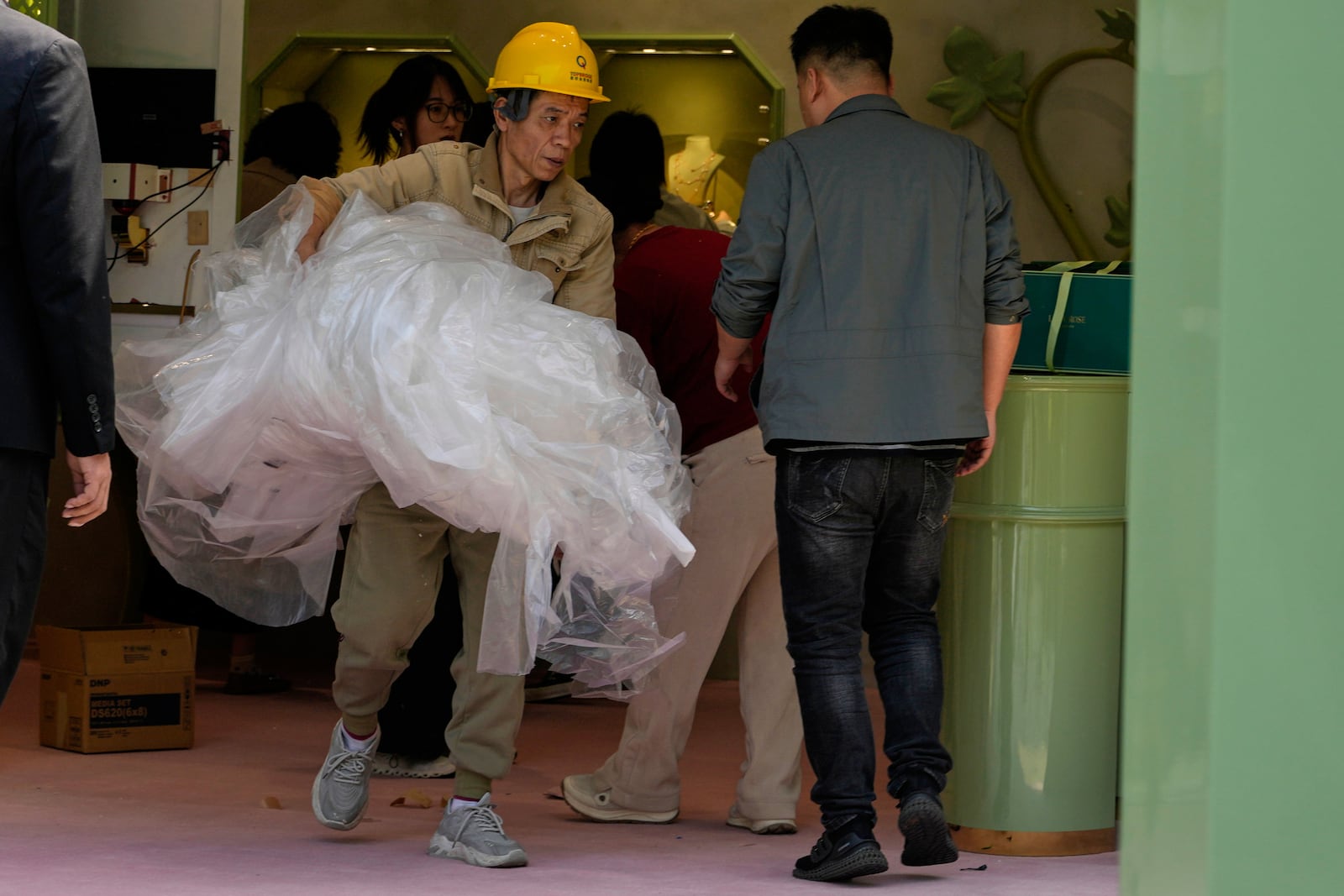 A worker removes plastic sheets after setting up a booth at a mall in Beijing, Wednesday, May 7, 2025. (AP Photo/Ng Han Guan)
