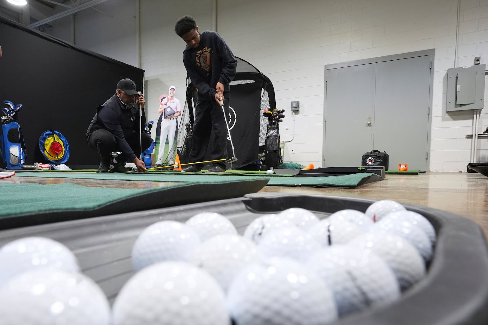 Shaun Horne, 16, a junior at Renaissance High School works on putting with golf coach Jess Hawkins in Detroit, Thursday, Feb. 27, 2025. (AP Photo/Paul Sancya)