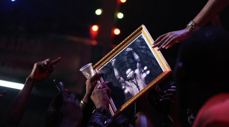 FILE - Singer Tiwa Savage hands back a portrait of Fela Anikulapo-Kuti to a fan at the New Afrika Shrine in Lagos, Nigeria, on Sunday, Oct. 21, 2012. (AP Photo/Jon Gambrell, File)