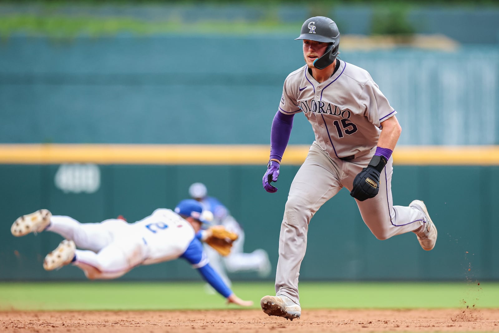 Colorado Rockies' Hunter Goodman (15) runs to third base on a single past Atlanta Braves shortstop Nick Allen, left, in the ninth inning of a baseball game, Saturday, June 14, 2025, in Atlanta. (AP Photo/Colin Hubbard)