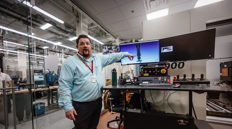 Material Research Engineer, Ryan Mooers points at a 3D computer generated image of an aircraft part. JIM NOELKER/STAFF
