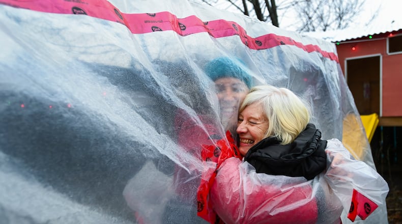 Carolyn Ellis, left, creator of the hug glove hugs her mother Susan Watts, 74, in her backyard on Christmas Eve during the COVID-19 pandemic in Guelph, Ont., Thursday, Dec. 24, 2020. Watts is a retired nurse who lives in an apartment near by and gets to come over outside and hug her daughter's family. (Nathan Denette/The Canadian Press via AP)