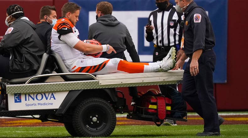 Cincinnati Bengals quarterback Joe Burrow (9) points to his knee as he is carted off the field after an injury in the second half of an NFL football game against the Washington Football Team, Sunday, Nov. 22, 2020, in Landover. (AP Photo/Andrew Harnik)