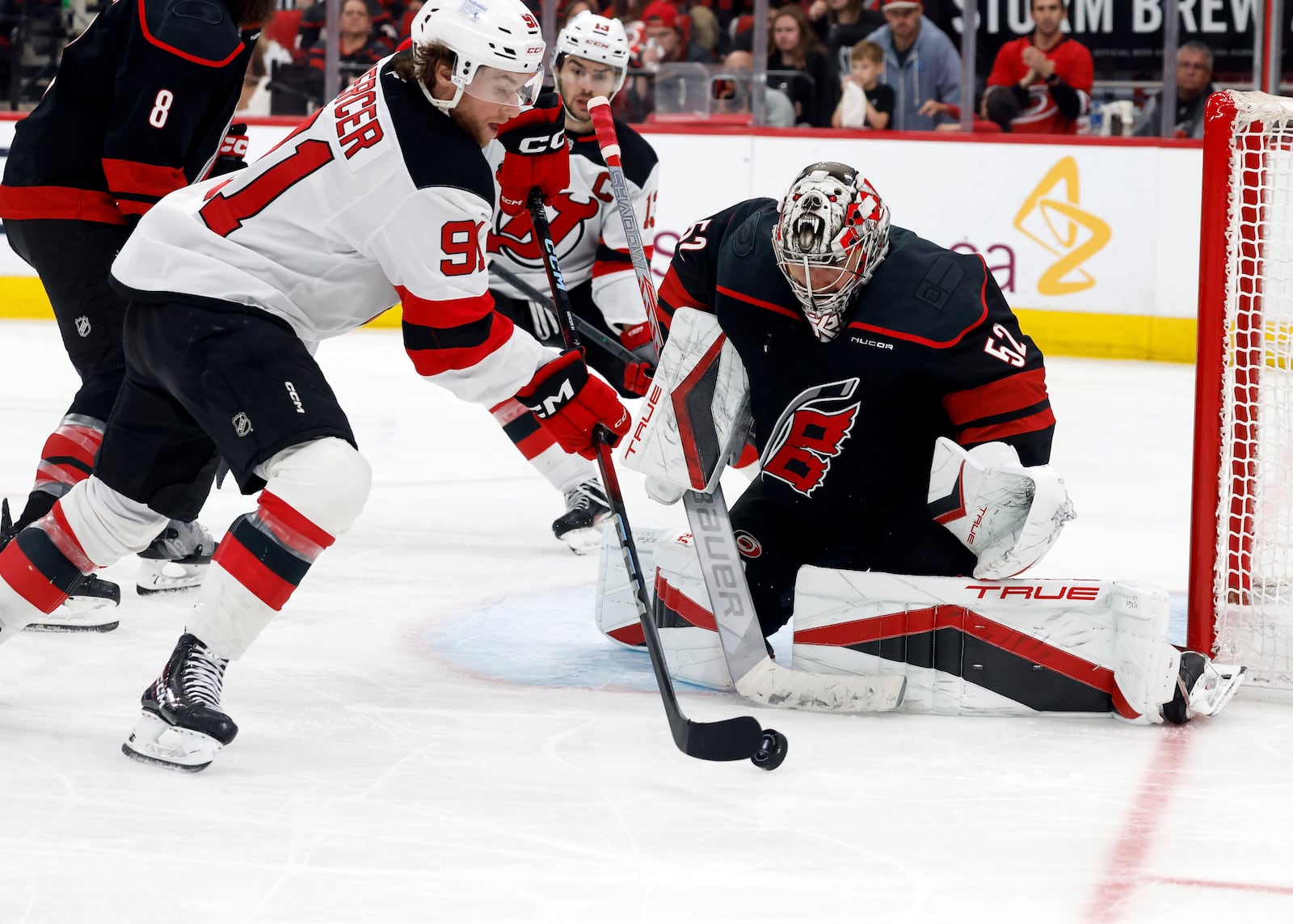 New Jersey Devils' Dawson Mercer (91) tries to settle the puck in front of Carolina Hurricanes goaltender Pyotr Kochetkov (52) during the third period of Game 5 of an NHL hockey Stanley Cup first-round playoff series in Raleigh, N.C., Tuesday, April 29, 2025. (AP Photo/Karl DeBlaker)