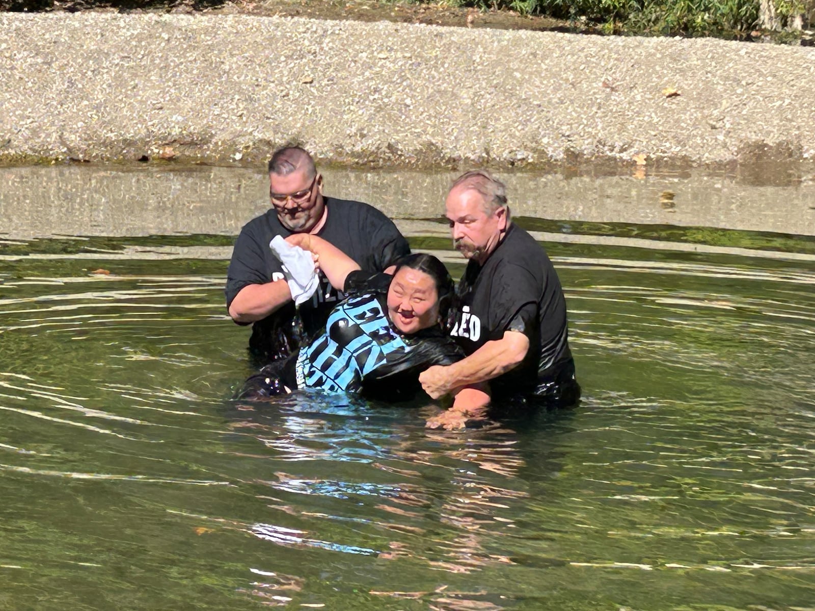 Pastor Chuck Hall, left, and Pastor John Ward, from Victory in God Church in Carlisle, help Faith Anne Ward stand up in Twin Creek last Sunday afternoon after she was baptized. RICK McCRABB/CONTRIBUTOR