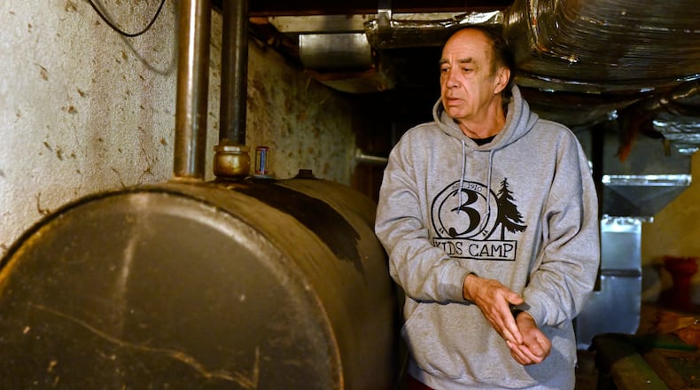 Mark Bain, who is part of the Low Income Home Energy Assistance Program, rubs his hands together as he checks the level on his oil at home in hopes that he will have enough oil to outlast the shutdown, in Bloomfield, Conn., Monday, Oct. 27, 2025. (AP Photo/Jessica Hill)