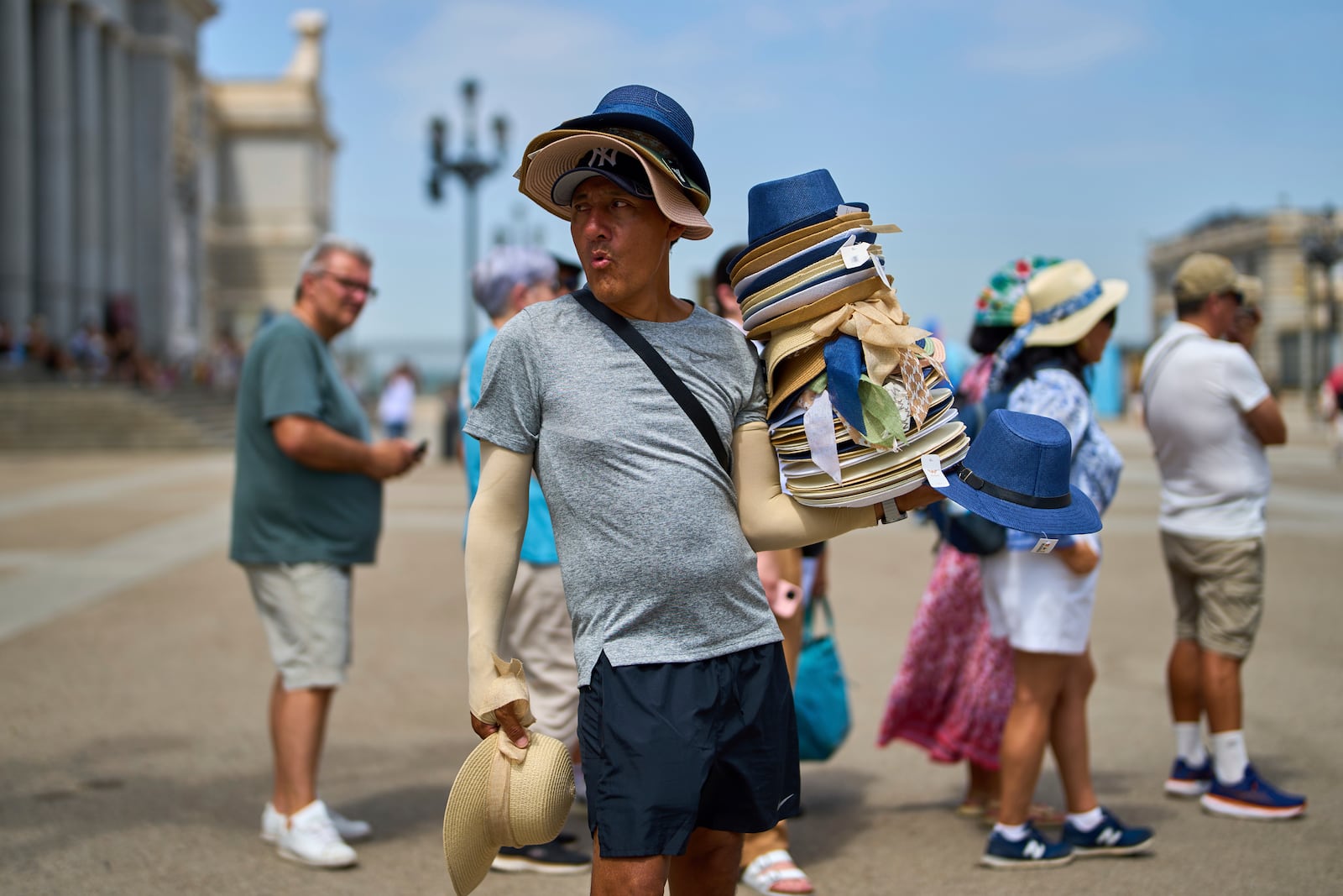A vendor sells hats during a heat wave in Madrid, Spain, Tuesday, July 1, 2025. (AP Photo/Manu Fernandez)