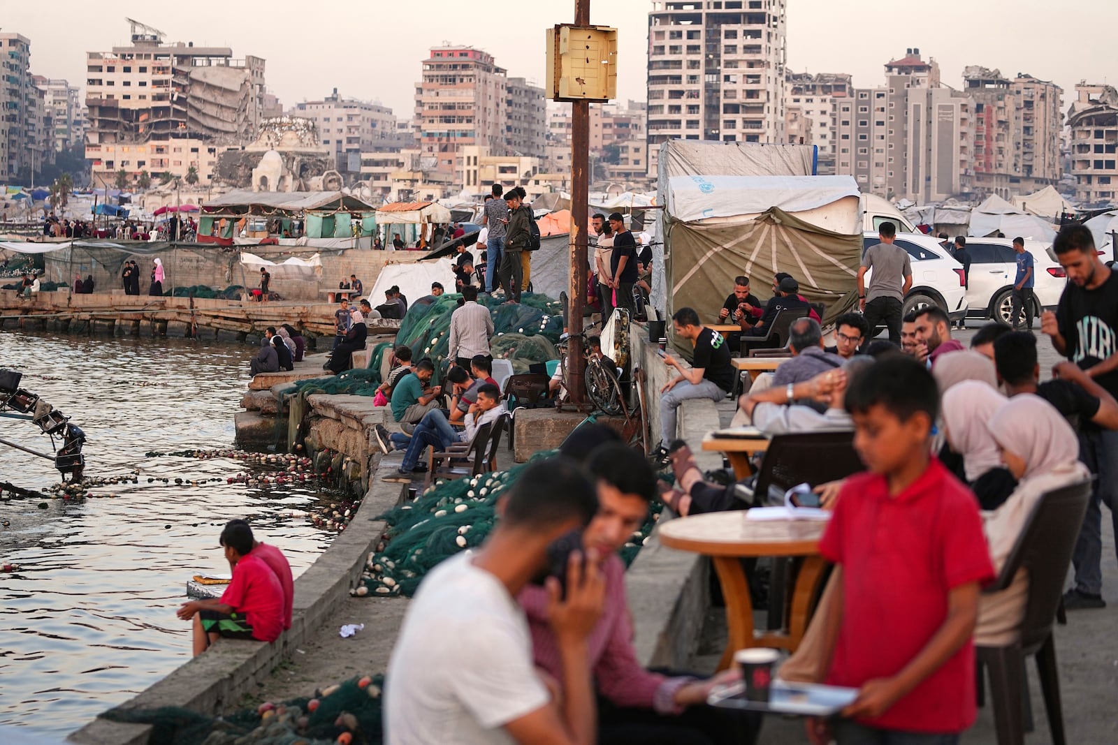 Palestinians spend time at the seafront next to a tent camp in the Gaza City port, Friday, June 13, 2025. (AP Photo/Jehad Alshrafi)