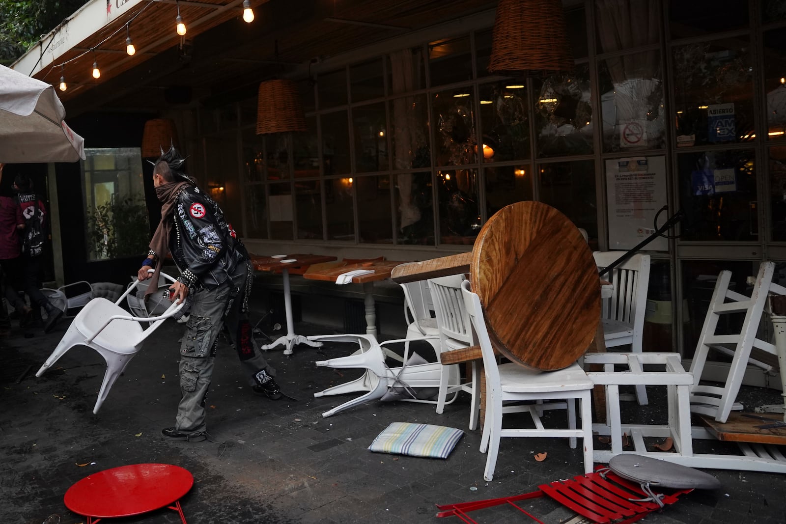 A demonstrator tosses a restaurant chair at the end of peaceful protest that turned violent against gentrification, as the increase in remote workers has risen prices and increased housing demand in neighborhoods like Condesa and Roma, in Mexico City, Friday, July 4, 2025. (AP Photo/Aurea Del Rosario)
