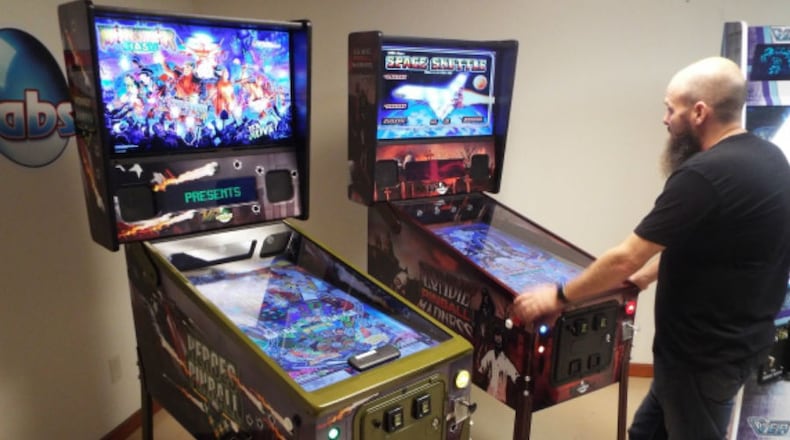 Brad Baker plays one of two versions of The Wizard, the most expensive but best-selling virtual pinball machine made by VPcabs, in the company’s Fairfield workshop. KEVIN EIGELBACH/WCPO