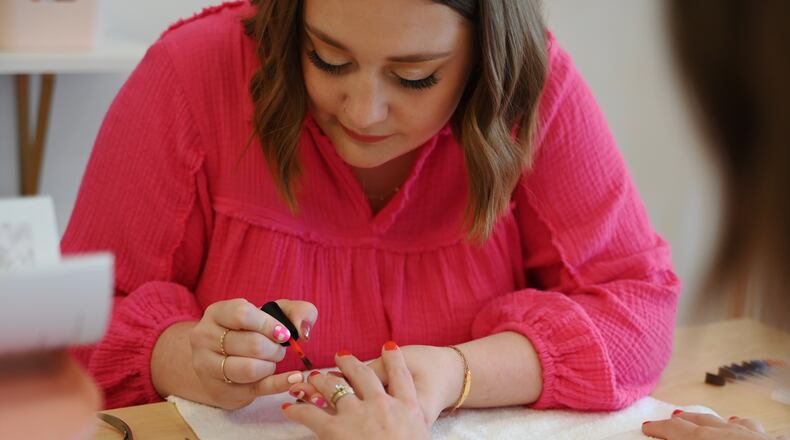 Abby O'Neal opens on July 13, 2024, Polished Hamilton inside her mom's business, Scripted Studio, 306 Main St., Hamilton. Pictured is O'Neal painting the nails of Vanessa Cannon, co-owner of True West Coffee. MICHAEL D. PITMAN/STAFF
