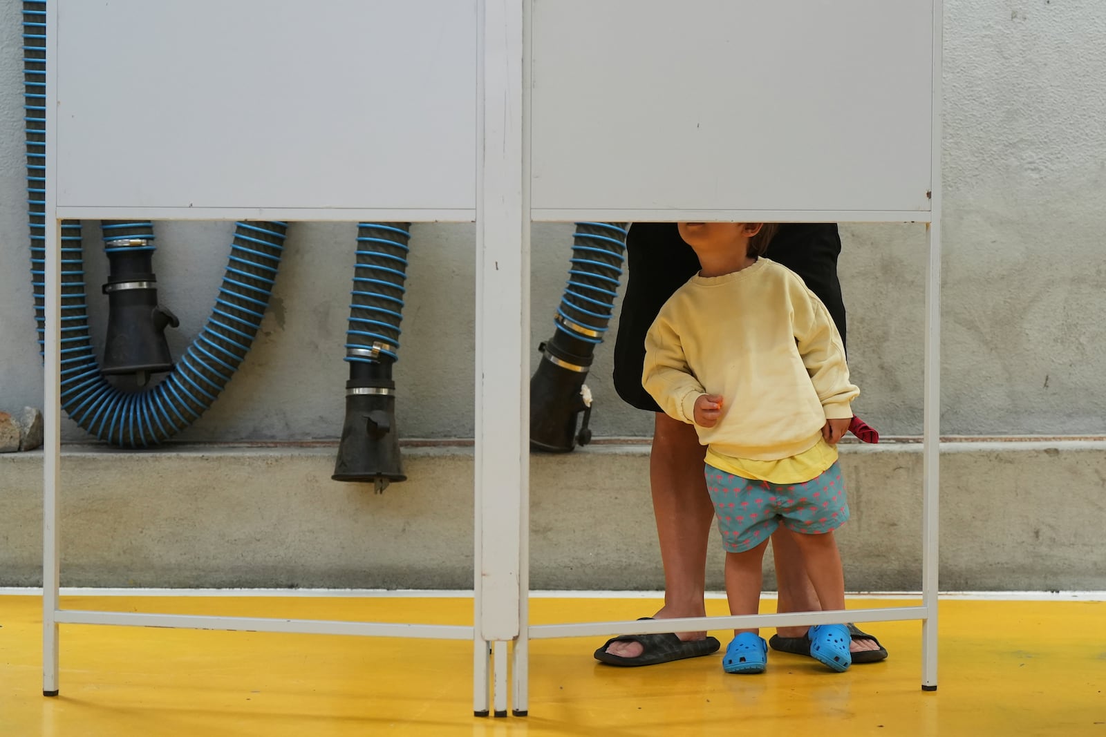 A child watches a voter fill their ballot in Portugal's general election at polling station in Lisbon, Sunday, May 18, 2025. (AP Photo/Ana Brigida)