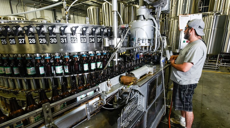 Rivertown Brewery owner Jason Roeper works the filling line at Rivertown Brewery & Barrel House Wednesday, June 14 in Monroe. NICK GRAHAM/STAFF