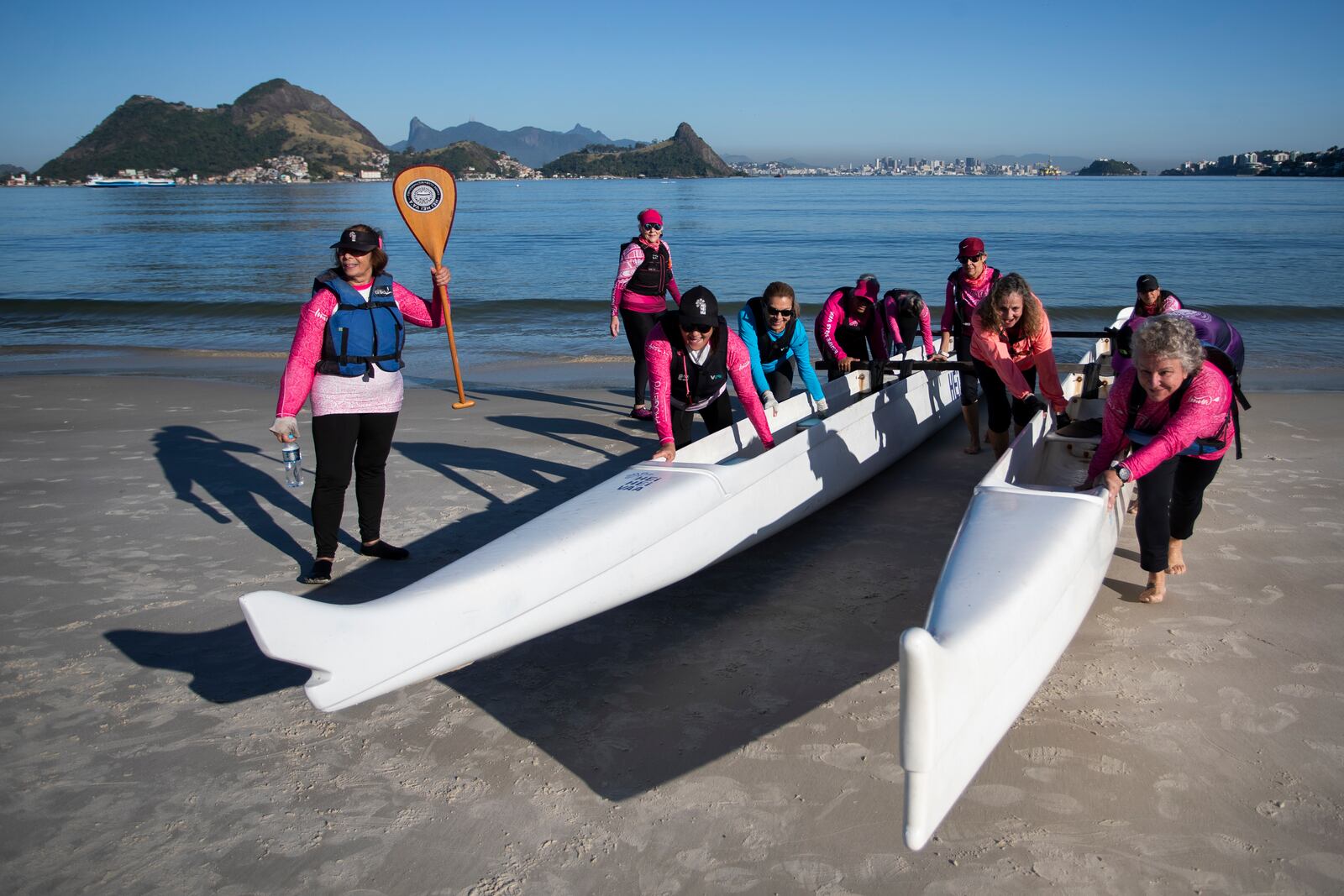The Rosas Va'a Hawaiian canoeing team, whose members are women who have undergone cancer treatment, push their canoes out of the water on to Charitas Beach after training in Niteroi, Rio de Janeiro state, Thursday, June 26, 2025. (AP Photo/Bruna Prado)
