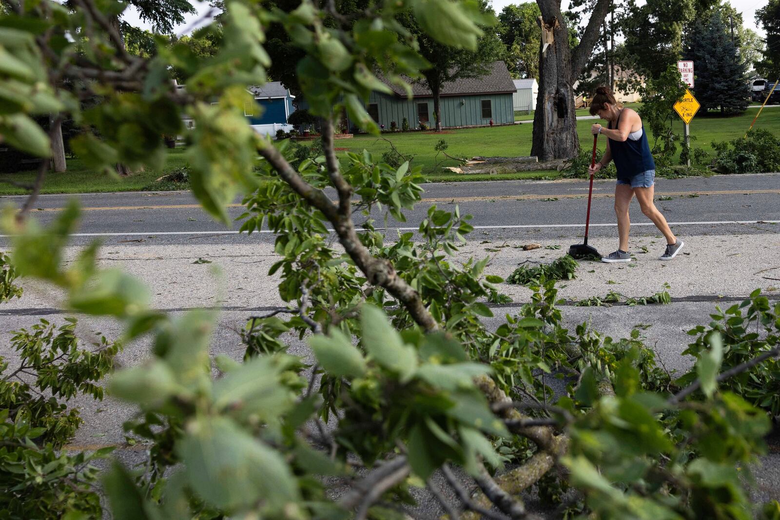 Dawn Sands cleans debris off Goddard Street on French Island after a storm with extreme winds in La Crosse, Wis., Tuesday, July 29, 2025. (Saskia Hatvany/La Crosse Tribune via AP)