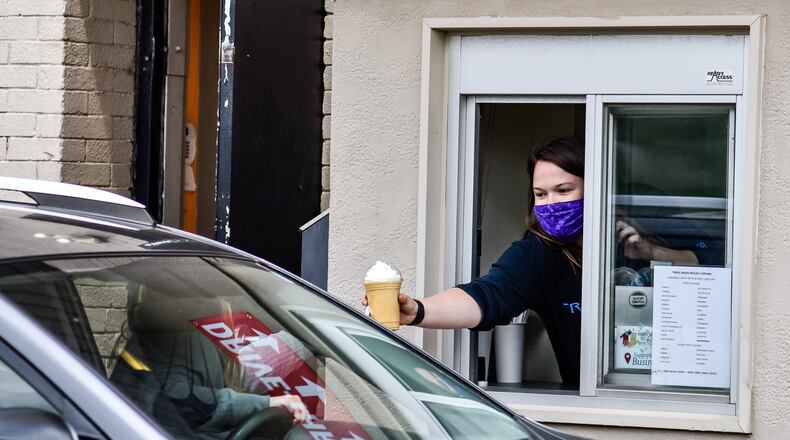 Samantha Maney takes orders at the drive through on Tuesday, the first day back open at Triple Moon Coffee Company in downtown Middletown. Triple Moon closed due to the coronavirus pandemic and has opened up for service at its drive through on the rear of the building. Downtown Middletown Inc. received $20,000 from the Middletown Community Foundation Coronavirus Emergency Fund to help those businesses with rent and utilities. NICK GRAHAM/STAFF