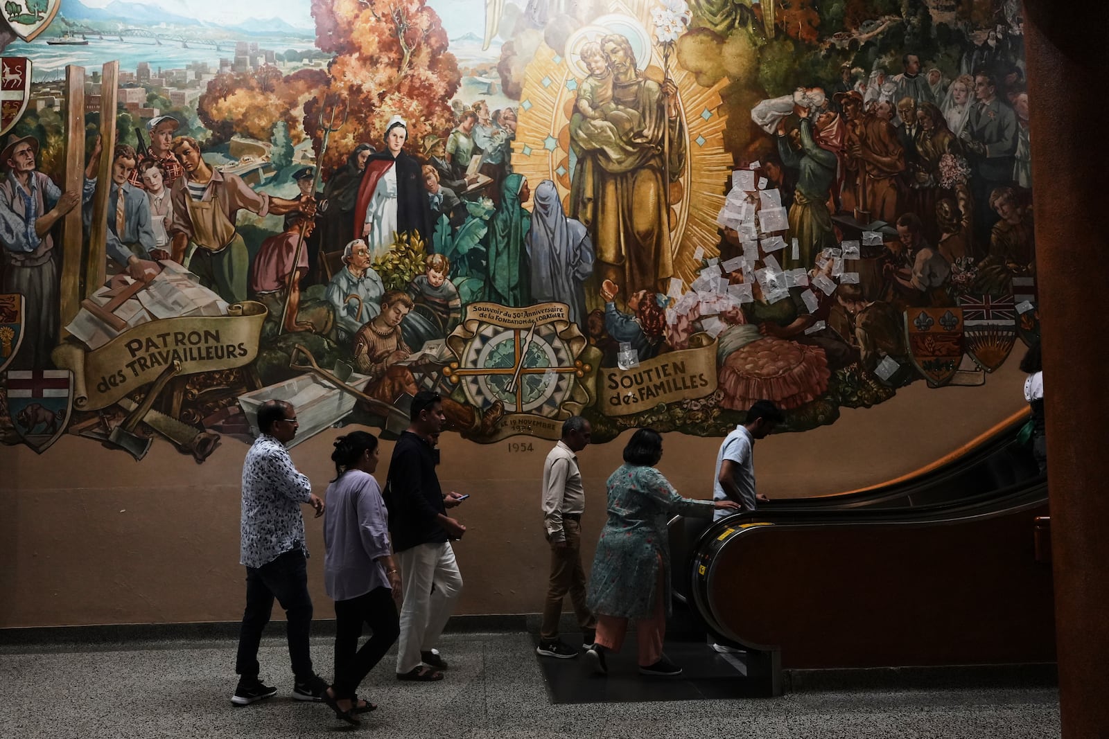 A mural that depicts St. Joseph, Patron of Workers, and others important to the city of Montreal, decorates a wall at the national shrine of Saint Joseph's Oratory of Mount Royal, in Montreal, Saturday, June 28, 2025. (AP Photo/Luis Andres Henao)