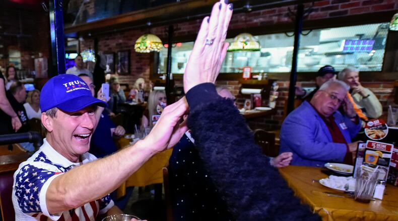 Mark Welch high-fives his wife Karen as a state is called in Donald Trump’s favor as they gather with other members of the Butler County Republican Party during an elections results watch party Tuesday, Nov. 8 at Uno Pizzeria and Grill in West Chester Township. NICK GRAHAM/STAFF
