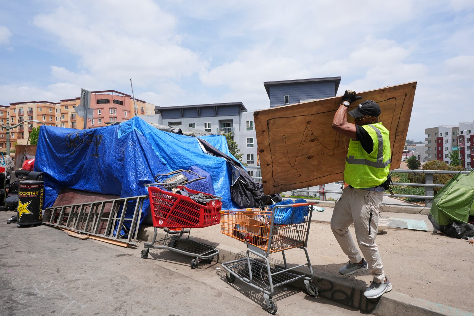 Jay Joshua cleans up around a homeless encampment where he currently lives, Monday, May 12, 2025, in Los Angeles. (AP Photo/Damian Dovarganes)