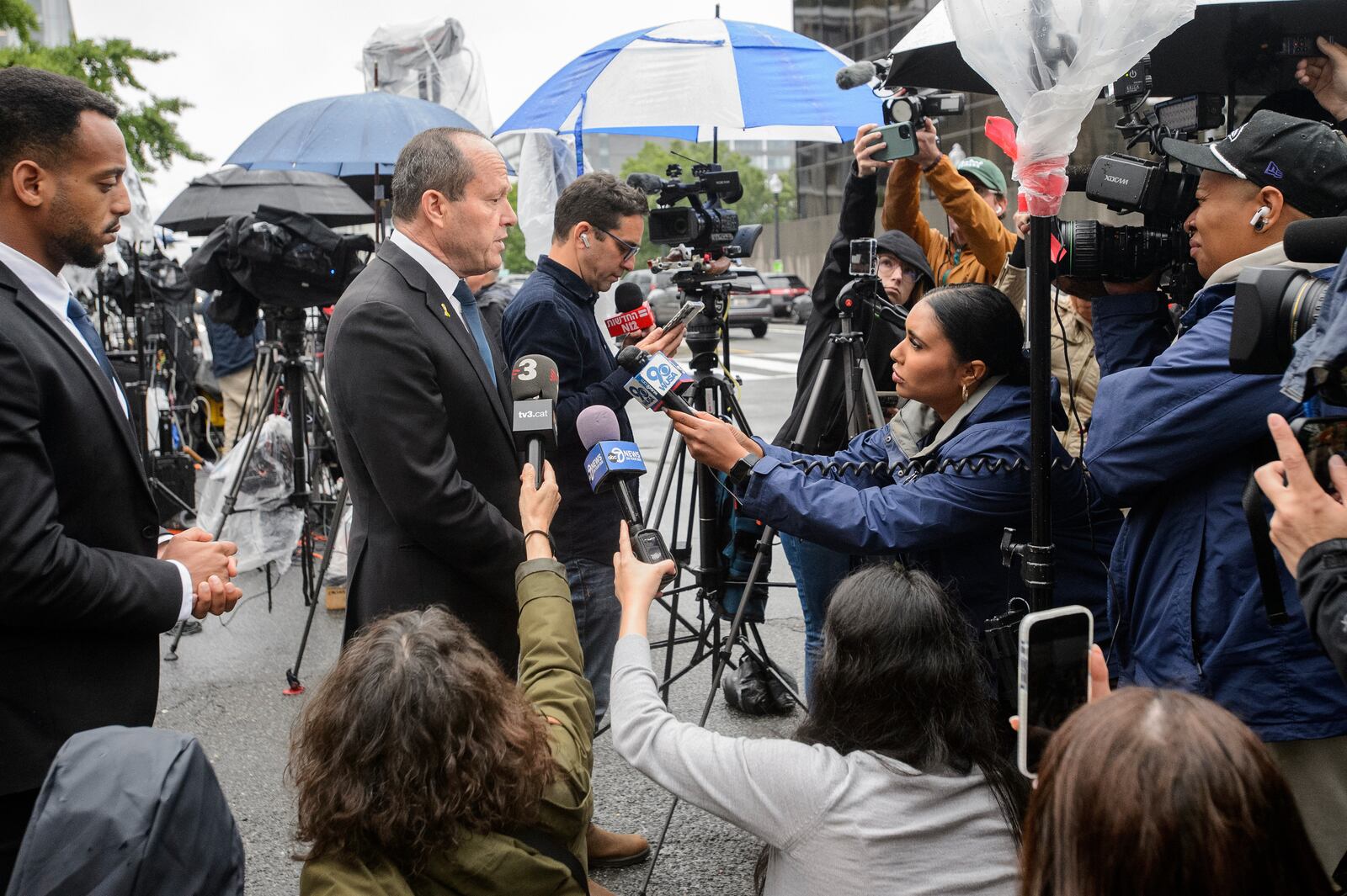 Israeli Minister of Economy and Industry Nir Barkat, center, talks with journalists at the scene as law enforcement work the area after two staff members of the Israeli Embassy in Washington were shot and killed outside the Capital Jewish Museum, Thursday, May 22, 2025, in Washington. (AP Photo/Rod Lamkey, Jr.)