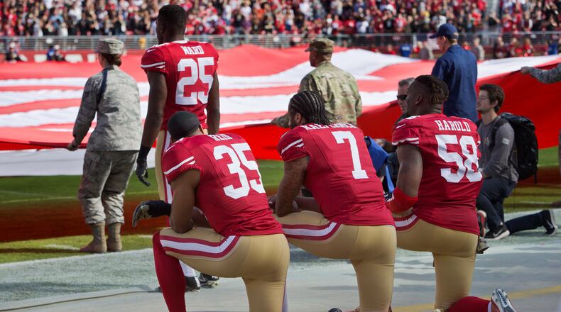 SANTA CLARA, CA - NOVEMBER 6:  Quarterback Colin Kaepernick #7, safety Eric Reid #35, and linebacker Eli Harold #58 of the San Francisco 49ers kneel before a game against the New Orleans Saints with the U.S. flag unfurled in honor of the armed services on November, 6 2016 at Levi's Stadium in Santa Clara, California.  The Saints won 41-23. (Photo by Brian Bahr/Getty Images)