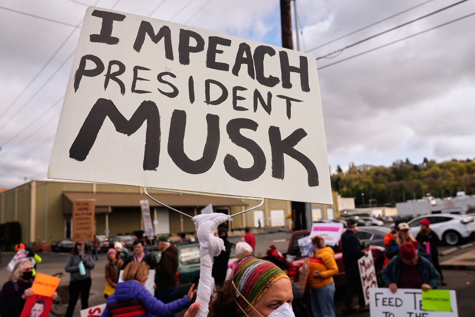 FILE - A person waves an "Impeach President Musk" sign during a protest, March 29, 2025, in Seattle. (AP Photo/Lindsey Wasson, File)