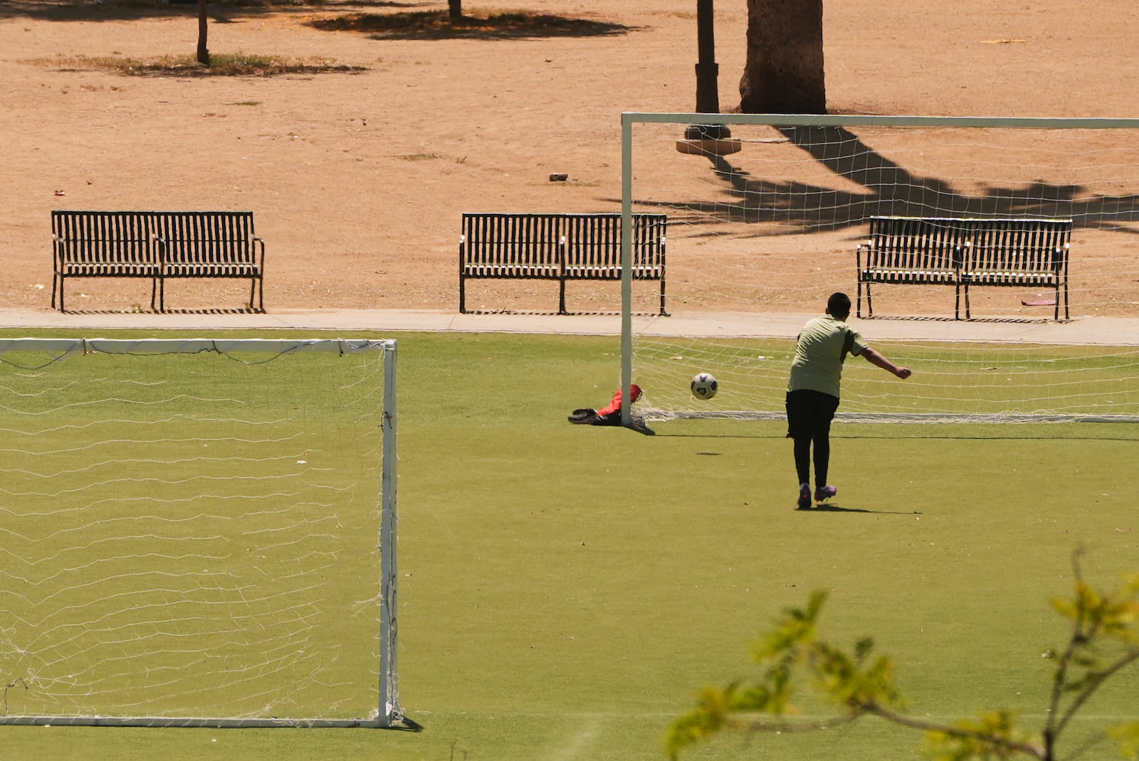 A boy kicks a soccer ball at MacArthur Park, Tuesday, July 8, 2025, in Los Angeles. (AP Photo/Damian Dovarganes)