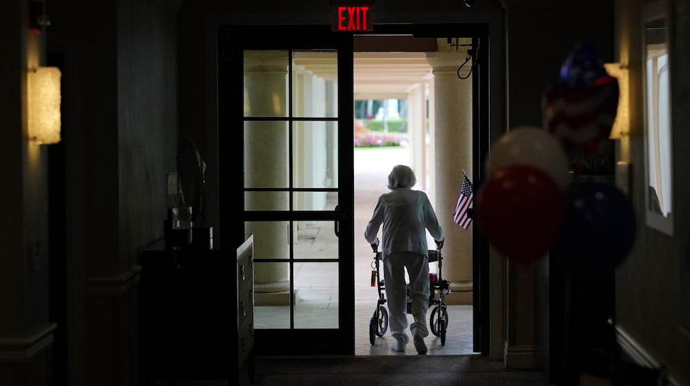 FILE - A woman uses a walker as she exits an assisted living building at the Toby and Leon Cooperman Sinai Residences, July 4, 2025, in Boca Raton, Fla. (AP Photo/Rebecca Blackwell, File)