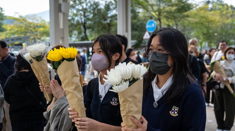 People offer flowers for the victims near the site of a deadly Wednesday fire at Wang Fuk Court, a residential estate in the Tai Po district of Hong Kong's New Territories on Monday, Dec. 1, 2025. (AP Photo/Chan Long Hei)