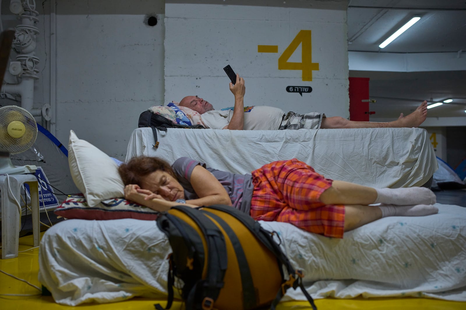 People spend the night in an underground parking garage as a precaution against possible Iranian missile attacks, in Tel Aviv, Israel, Monday, June 23, 2025. (AP Photo/Ohad Zwigenberg)